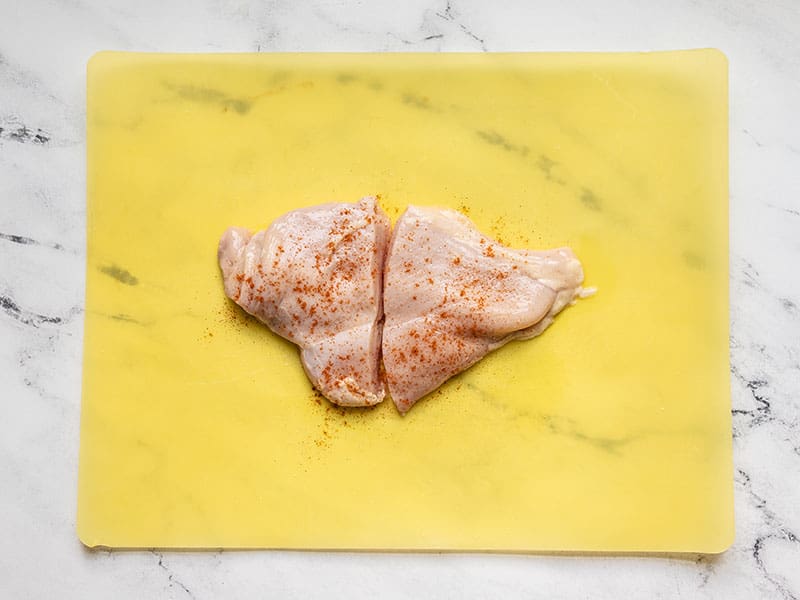 Cut and seasoned chicken breast on cutting board