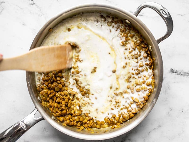 Coconut milk being stirred into the skillet