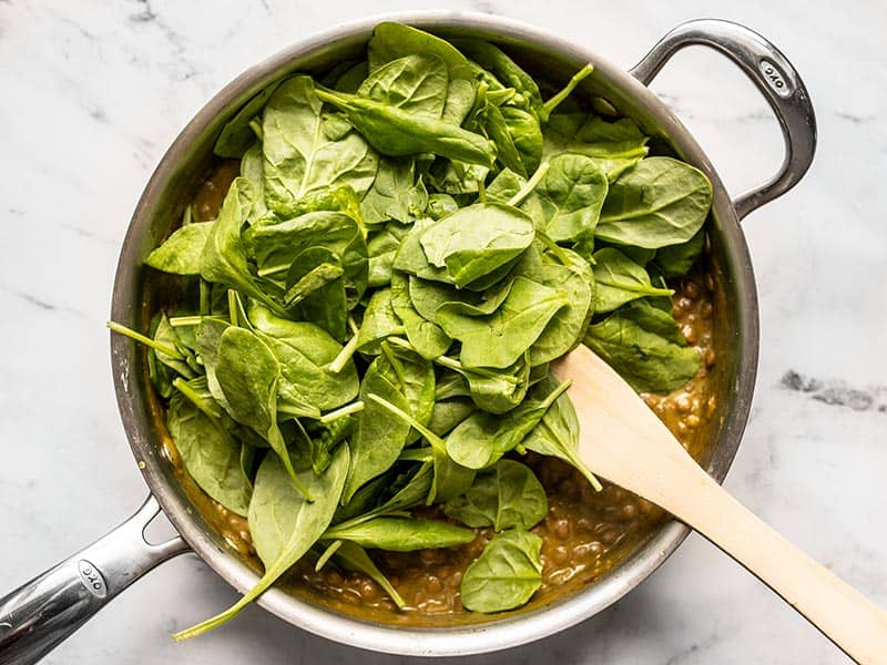 Fresh spinach added to the skillet