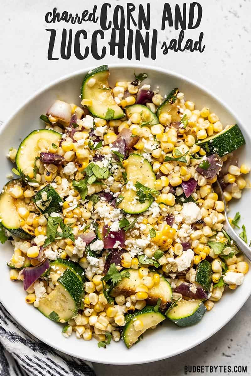 Overhead view of a large bowl full of Charred Corn and Zucchini Salad with title text overlay at the top.