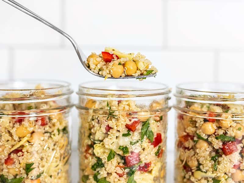 Lemony Artichoke and Quinoa Salad in mason jars, a forkful hovering above.