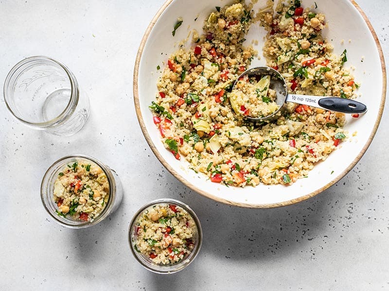 Lemony Artichoke and Quinoa Salad being portioned into mason jars