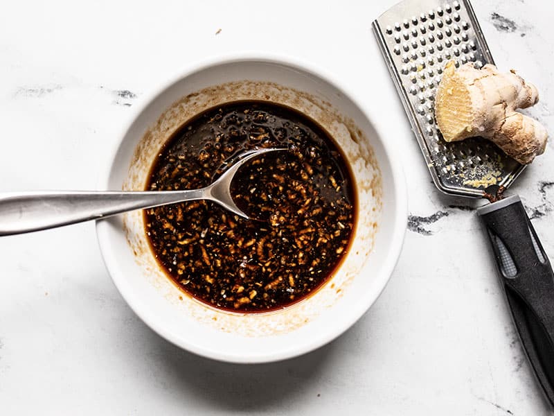 Soy Ginger Glaze in a bowl with a spoon, ginger root on the side.