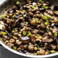 Close up side view of Soy Glazed Eggplant in the skillet, topped with peanuts and green onion