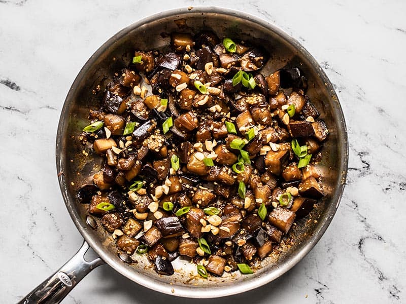 Soy Glazed Eggplant topped with green onion and peanuts in the skillet.