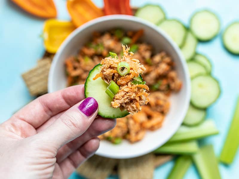 Close up view of Sweet and Spicy Tuna Salad on a slice of cucumber, the bowl in the background.