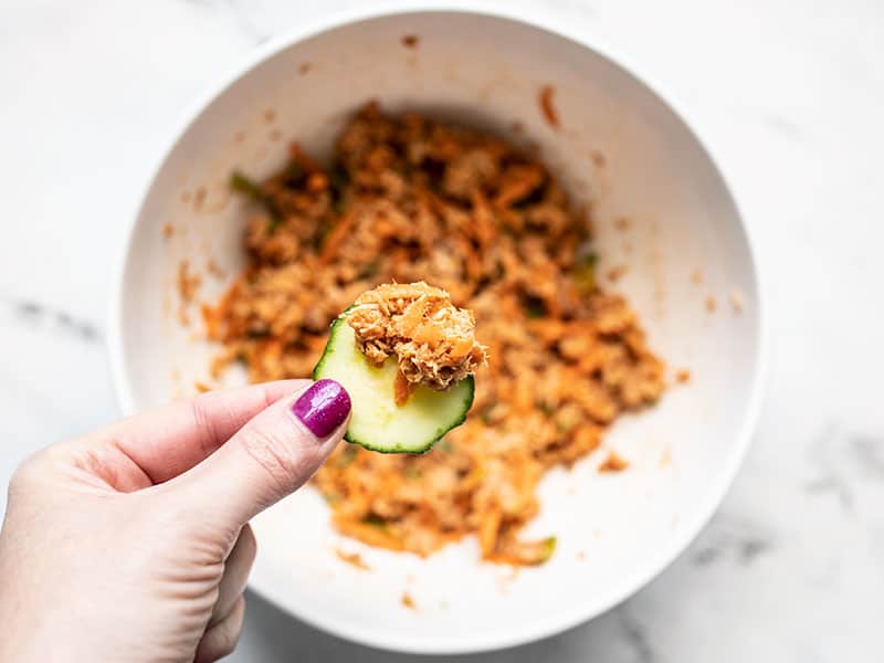 A cucumber dipped into the sweet and spicy tuna salad bowl