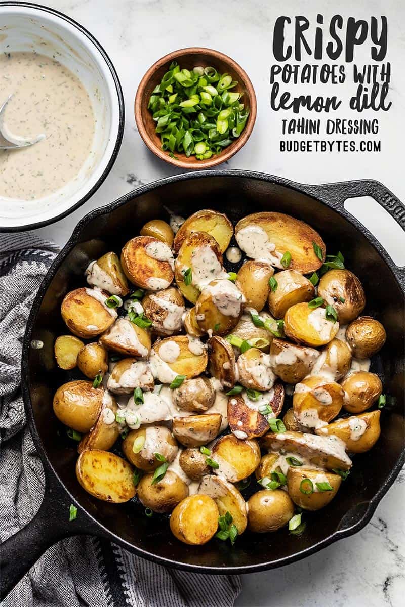 Overhead view of a cast iron skillet containing crispy potatoes with lemon dill tahini dressing, title text at the top