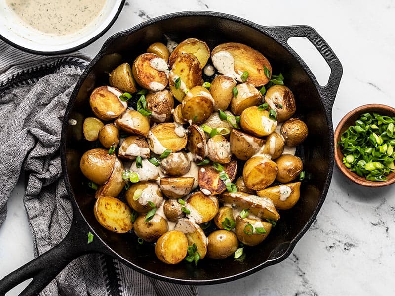 Finished crispy potatoes with lemon dill tahini dressing and sliced green onions