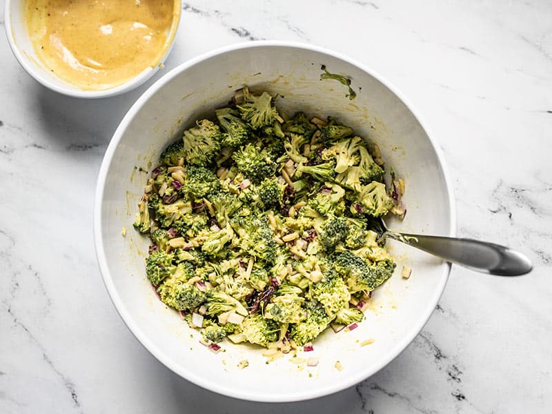 Finished honey mustard broccoli salad with the remaining honey mustard dressing in a bowl on the side.