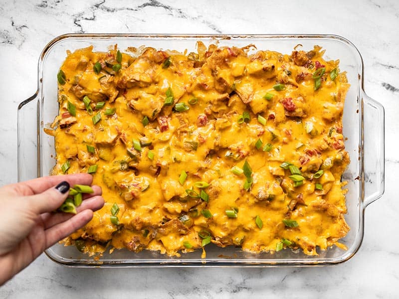 Sliced green onion being added to the top of the baked King Ranch Chicken Casserole