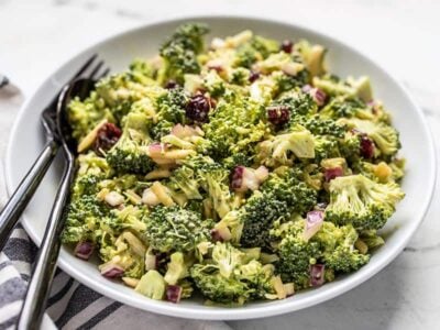 Front view of a bowl of Honey Mustard Broccoli Salad with a black fork and spoon in the side of the bowl.