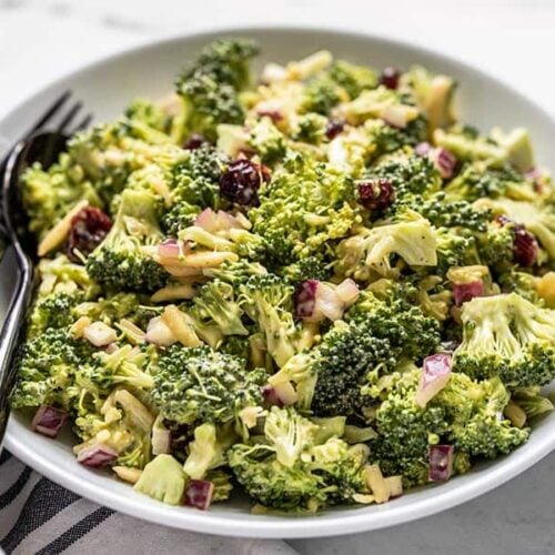 Front view of a bowl of Honey Mustard Broccoli Salad with a black fork and spoon in the side of the bowl.