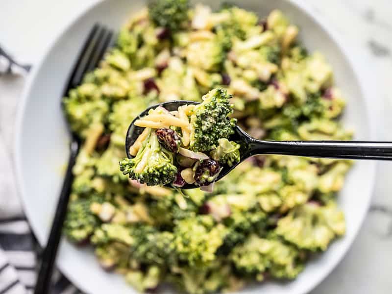 Close up of a spoonful of Honey mustard Broccoli Salad with the bowl in the background