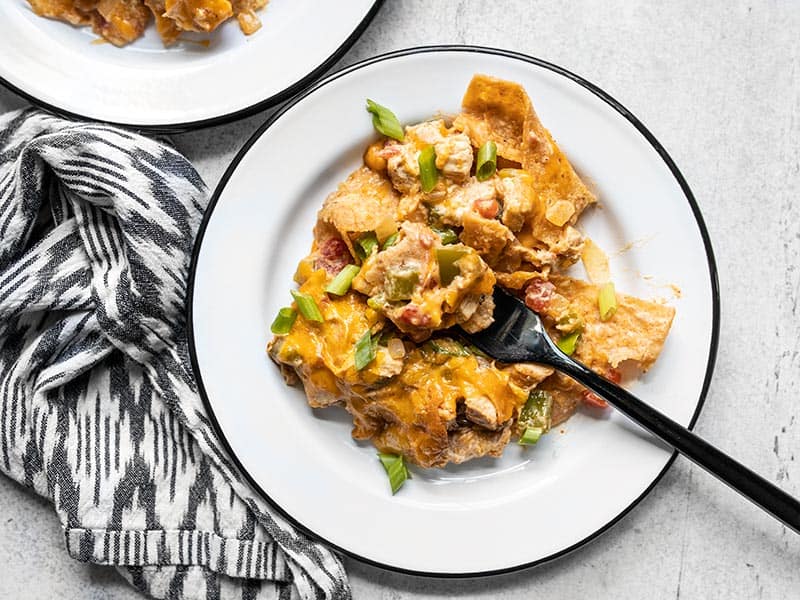 This made from scratch King Ranch Chicken Casserole has layers of chicken, tortillas, cheese, and a creamy sauce, with NO canned soups! BudgetBytes.com Close up of a plate full of King Ranch Chicken Casserole with a fork stuck in the middle