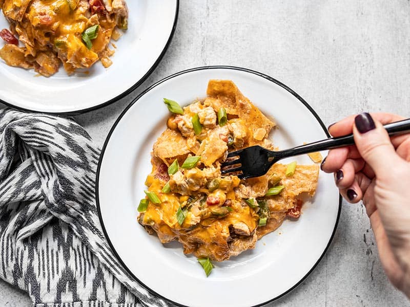This made from scratch King Ranch Chicken Casserole has layers of chicken, tortillas, cheese, and a creamy sauce, with NO canned soups! BudgetBytes.com Two plates with King Ranch Chicken Casserole, a fork digging into one of them.