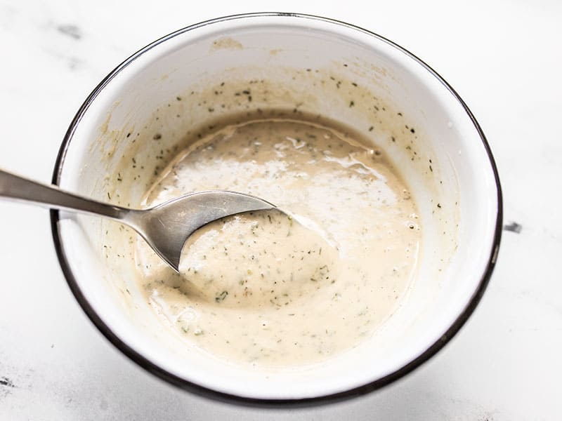 A spoon dipping into a bowl of Lemon Dill Tahini Dressing