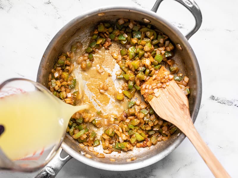 Chicken broth being poured into the skillet