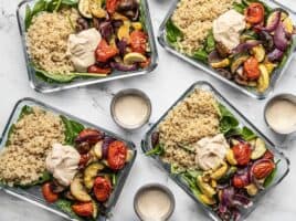 Four glass containers with Roasted Vegetable Salad and three dressing containers