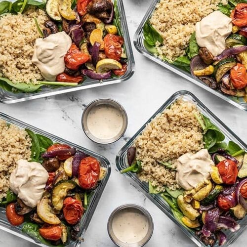 Four glass containers with Roasted Vegetable Salad and three dressing containers