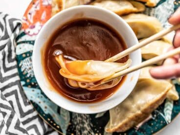 Close up of a dumpling being dipped into a bowl of Simple Sweet and Sour Sauce