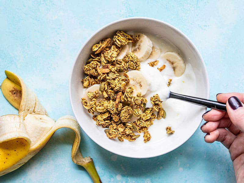 A bowl of yogurt with banana slices and Super Crunchy Oil Free Granola