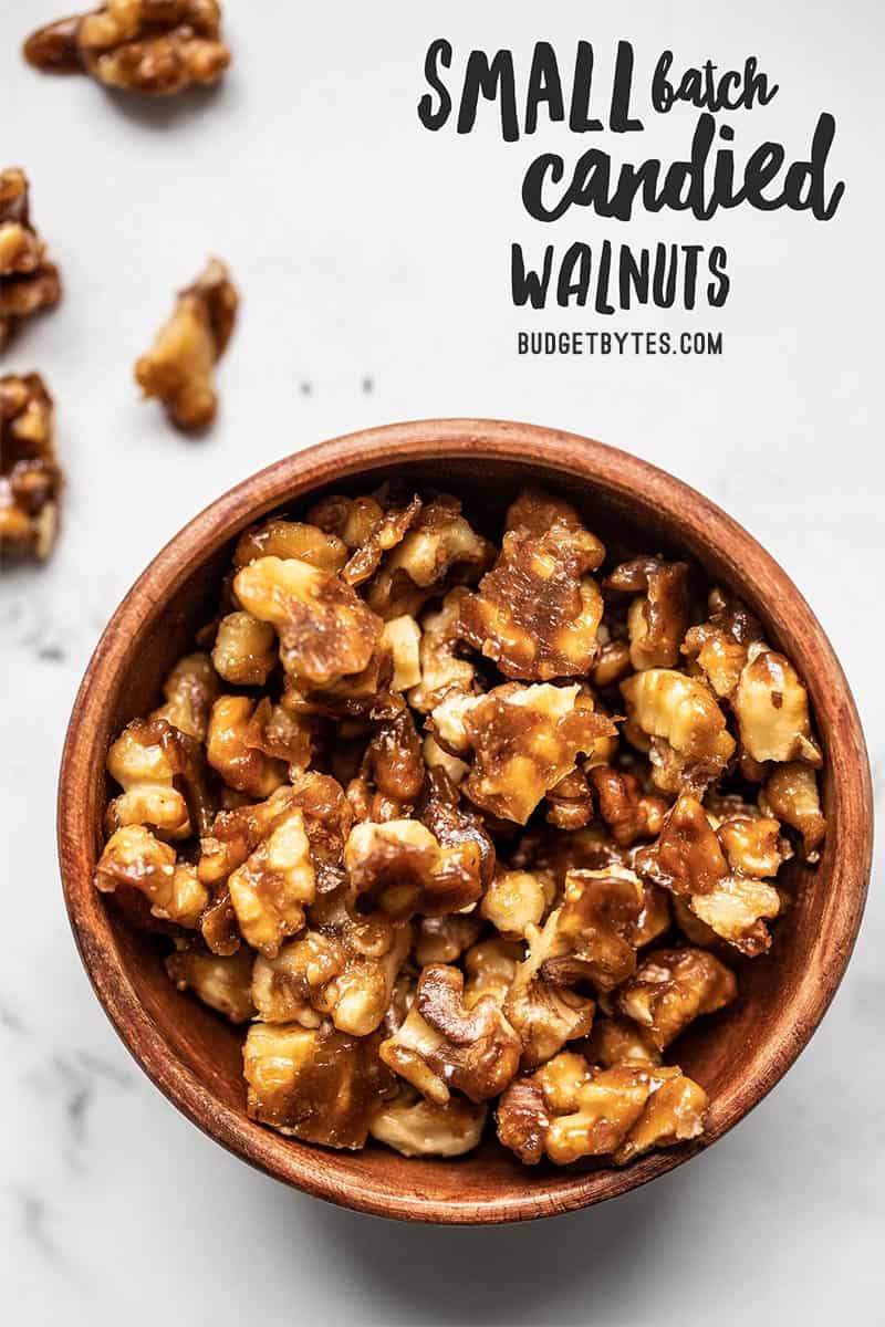 Overhead view of a small wooden bowl full of candied walnuts with title text overlay at the top