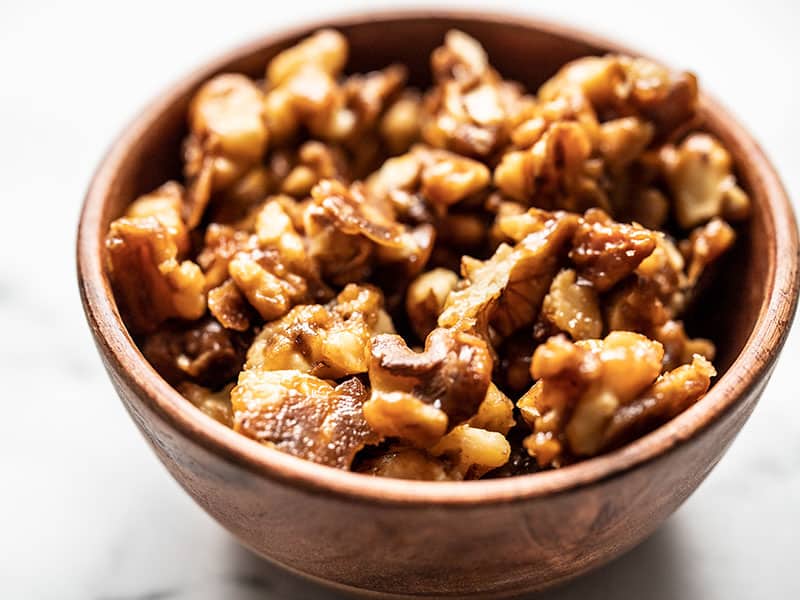 Close up of crunchy candied walnuts in a small wooden bowl