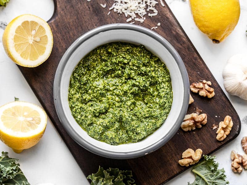 overhead view of a bowl of kale pesto surrounded by the ingredients