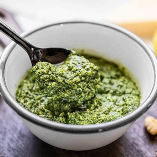 Side view of a spoonful of kale pesto being lifted from the bowl.