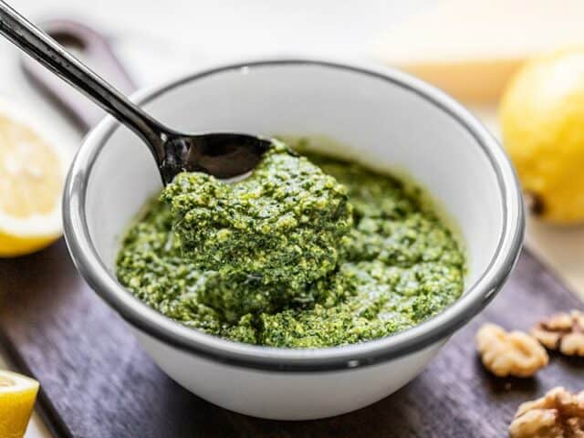 Side view of a spoonful of kale pesto being lifted from the bowl.