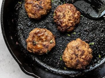 Close up of four Maple Sage Breakfast Sausages in a cast iron skillet