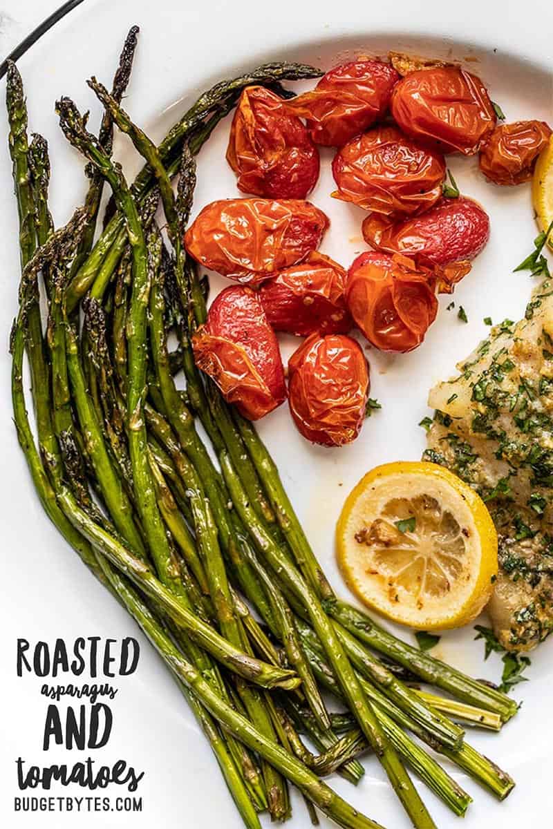 Close up of roasted asparagus and tomatoes on a dinner plate with title text in the bottom corner