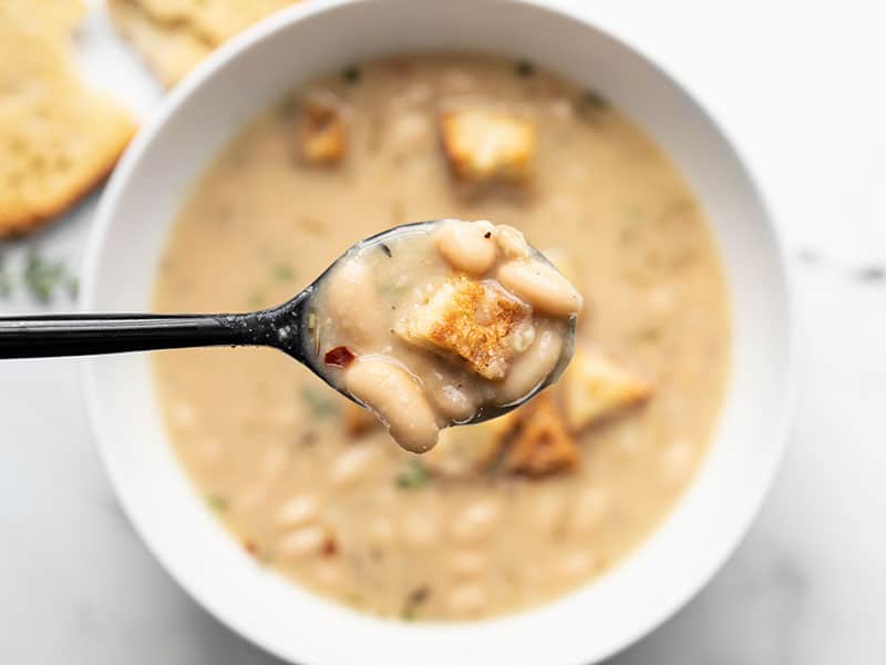 Close up of a spoonful of rosemary garlic white bean soup.