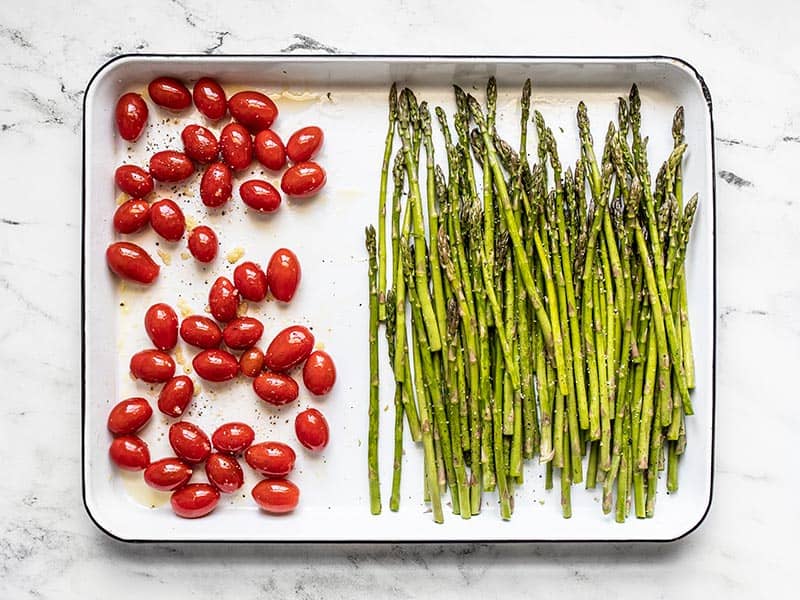 Asparagus and tomatoes seasoned and ready to roast