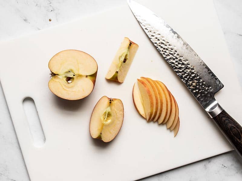 Sliced jazz apple on a cutting board with a chef's knife.