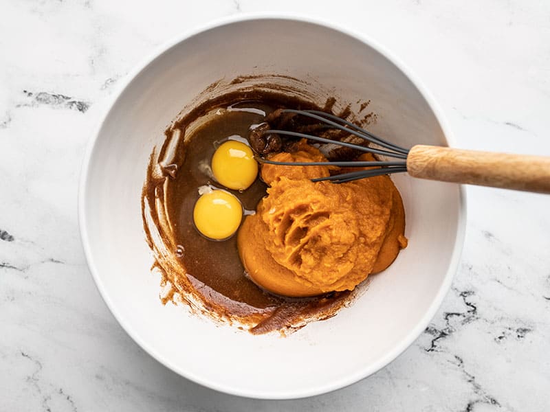 Eggs and pumpkin in bowl with butter and sugar mixture