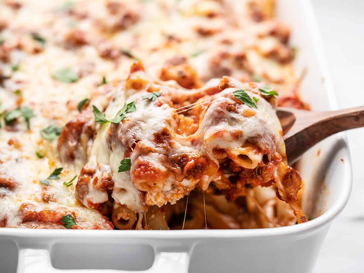 Side view of baked ziti being lifted out of the casserole dish. 