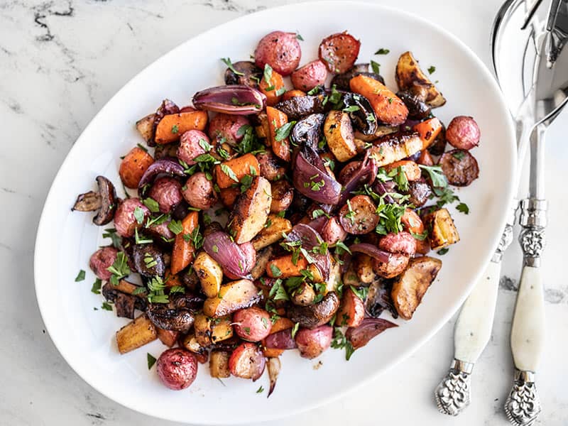 Balsamic roasted vegetables plated on a platter with chopped parsley on top