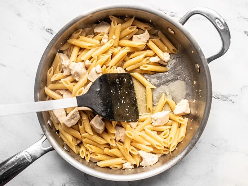 Cooked pasta in the skillet with a spatula pulling the pasta to the side to show no broth remains