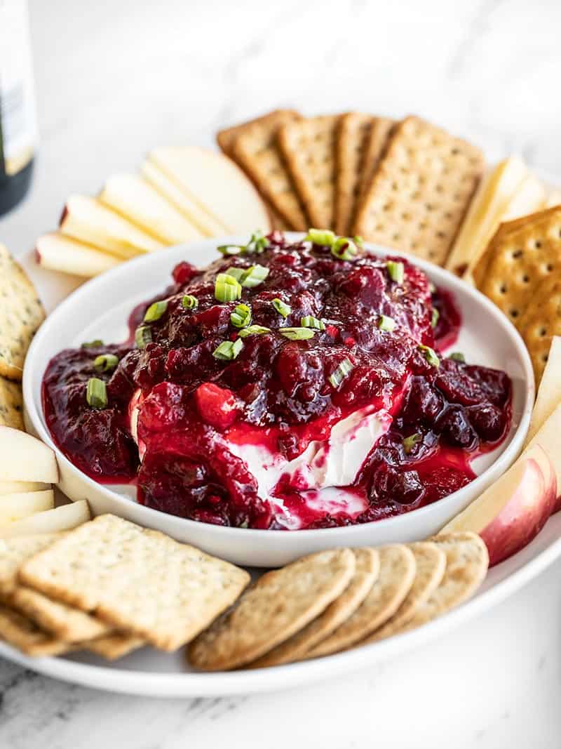 Front view of a cranberry cream cheese dip platter with crackers and apple slices