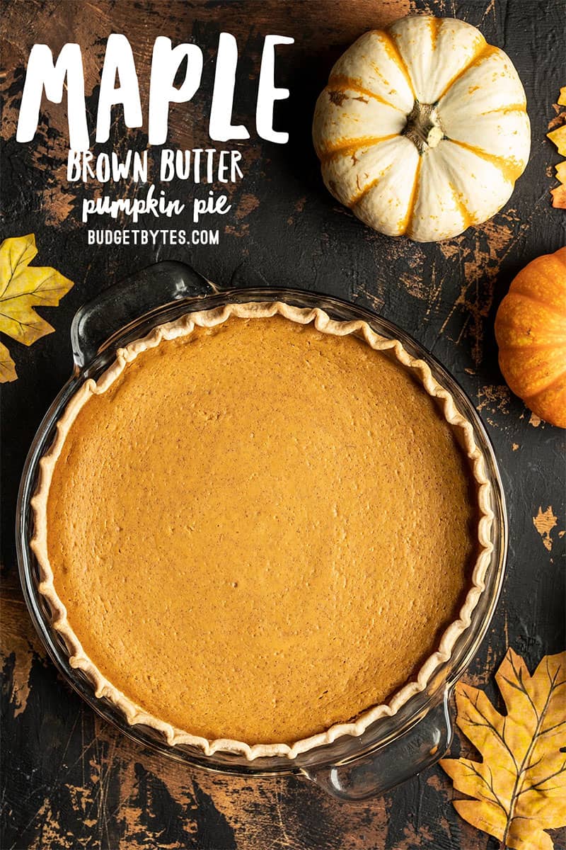 A whole Maple Brown Butter Pumpkin Pie with mini pumpkins on the side