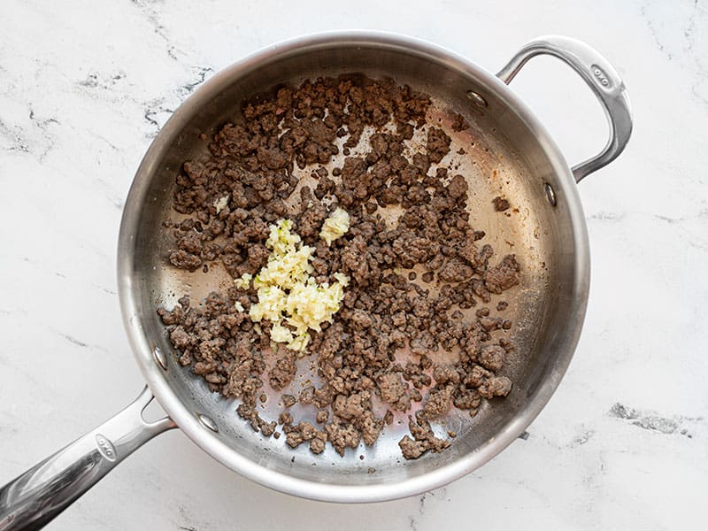 Browned beef and minced garlic in a skillet