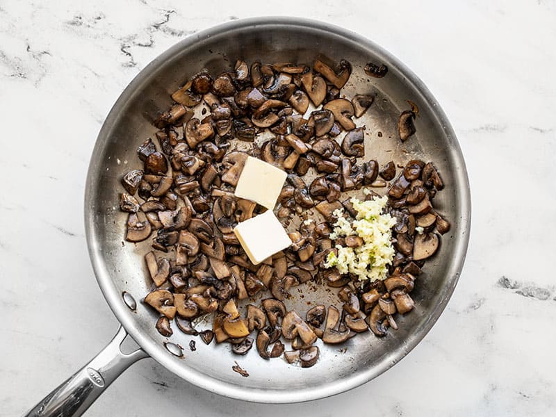 Butter and garlic added to the skillet with mushrooms