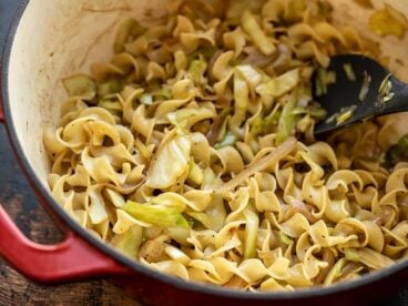 Close up of fried cabbage and noodles in a large pot, from the side