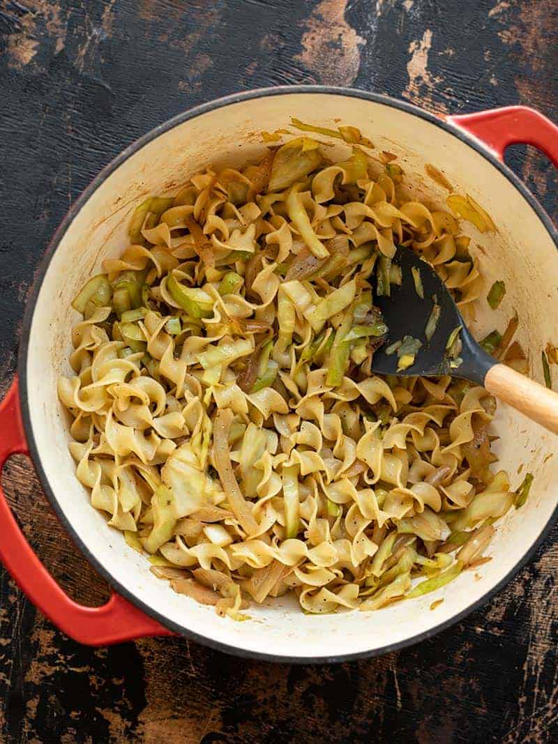 Fried Cabbage and Noodles in a large red pot with a silicone spoon.