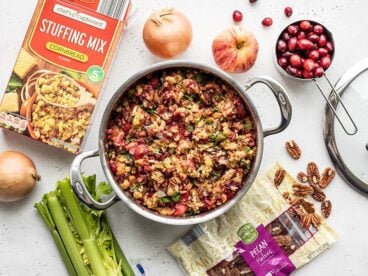 Overhead view of a pot full of Roasted Apple Cranberry Cornbread Stuffing with ingredients scattered all around