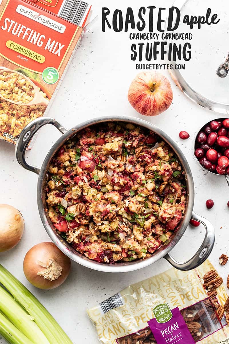 A pot of Roasted Apple Cranberry Cornbread Stuffing with ingredients all around, title text at the top