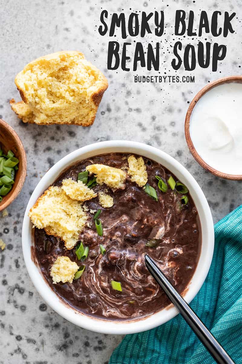 One bowl of smoky black bean soup with sour cream and a crumbled corn muffin