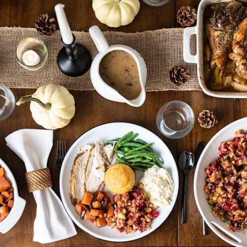 A full Thanksgiving dinner plate on a table with other Thanksgiving dishes